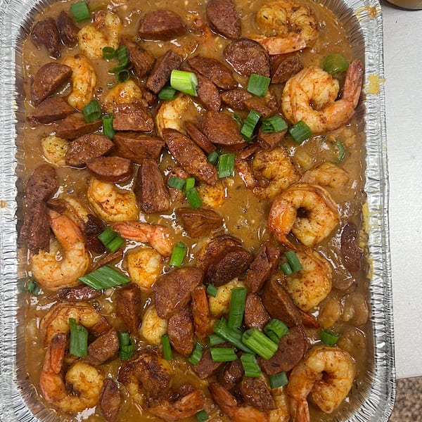 Cathy's Kitchen's shrimp and sausage gumbo, garnished with green onions in a foil pan.