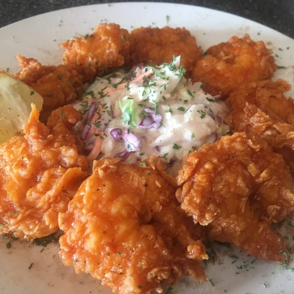 Cathy's Kitchen's fried chicken pieces arranged around a mound of coleslaw with a lemon wedge.