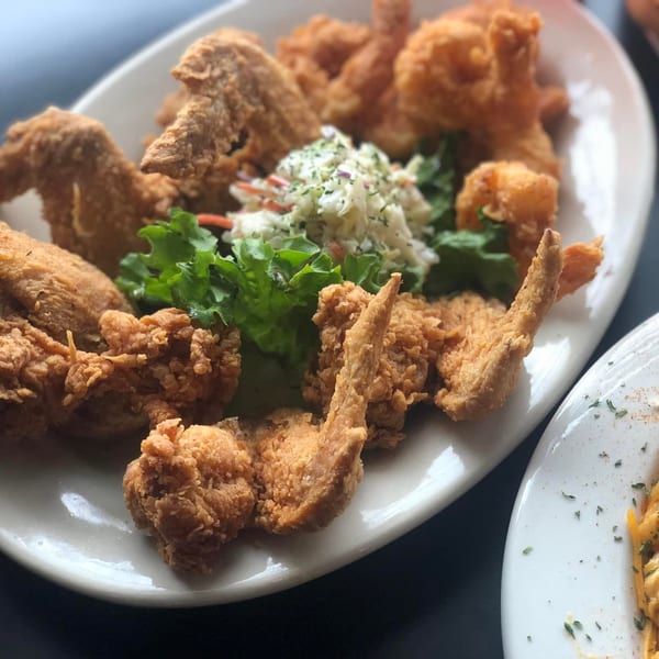 A platter of golden-brown fried chicken, coleslaw, and lettuce from Cathy's Kitchen.
